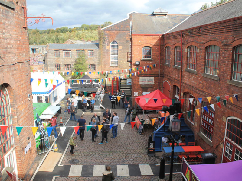 Steel City Beer & Cider Festival at Kelham Island Museum — bunting, food stalls, and real ale in Sheffield's industrial courtyard.